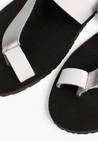Black flip-flops with a textured sole, featuring white and silver straps. The upper straps have a smooth finish, while the sole is flat.