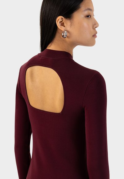 Top a maniche lunghe color marsala con un design unico sulla schiena aperta, caratterizzato da un morbido tessuto beige in contrasto sotto il taglio.