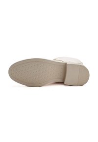 Suela de zapato de goma beige con una superficie texturizada de patrón en diamante, punta redondeada y un leve tacón.