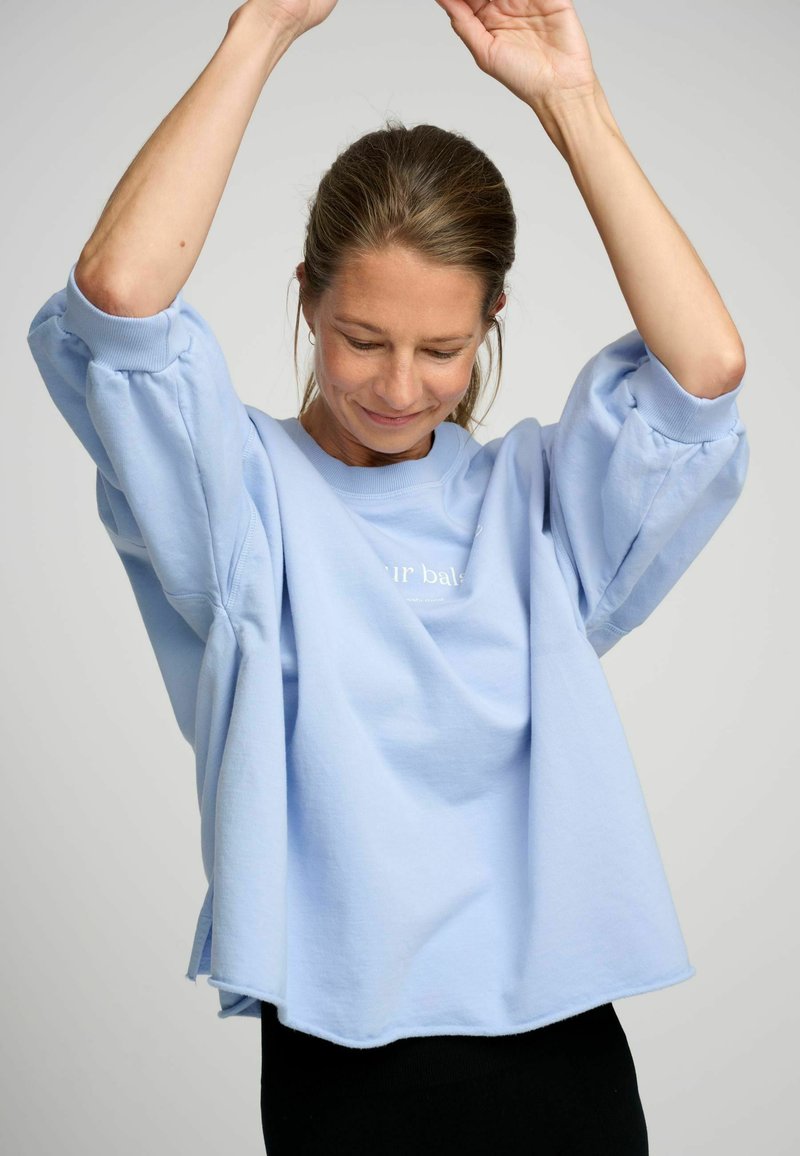 Lichtblauwe sweatshirt met een ontspannen pasvorm, voorzien van oversized pofmouwen, geribbelde manchetten en een subtiele print op de voorkant.