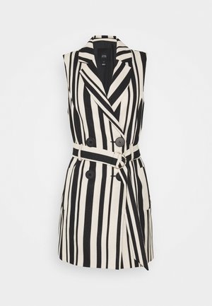 Sukienka typu blezer bez rękawów z pionowymi czarno-białymi paskami, dwurzędowymi guzikami i pasem z metalową klamrą.