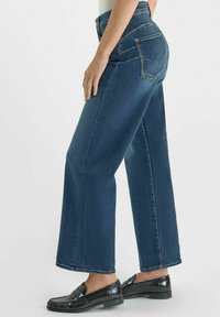 Hoggetaille blauwe denim jeans met een losse pasvorm, met grote achterzakken en een rechte pijpdesign. Gecombineerd met zwarte loafers.