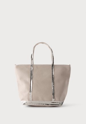 Sac tote beige avec bordure en sequins argentés brillants sur les anses et le bas, présenté sur un fond uni clair.