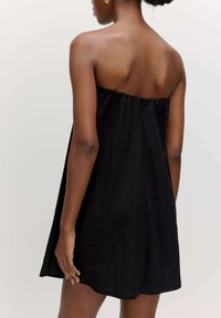 Zwarte strapless jurk van textuurstof, met een losse pasvorm en een zoom die boven de knie valt, met een eenvoudig ontwerp.