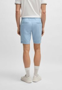 Ljusblå shorts gjorda av ett slätt tyg, med två bakfickor och en bekväm passform. Bärs med vita strumpor och neutrala sneakers.