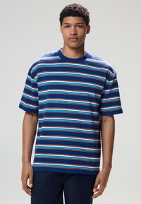 Kortærmet t-shirt med rund hals og vandrette striber i blå, lyseblå, orange og hvid på en marineblå baggrund. Fremstillet af bomuld.