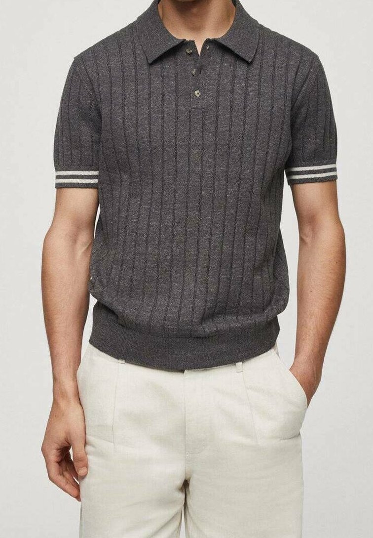 Polo à manches courtes, gris foncé, avec des rayures verticales, un patte de boutonnage à trois boutons et des poignets rayés ; porté avec un pantalon de couleur claire.