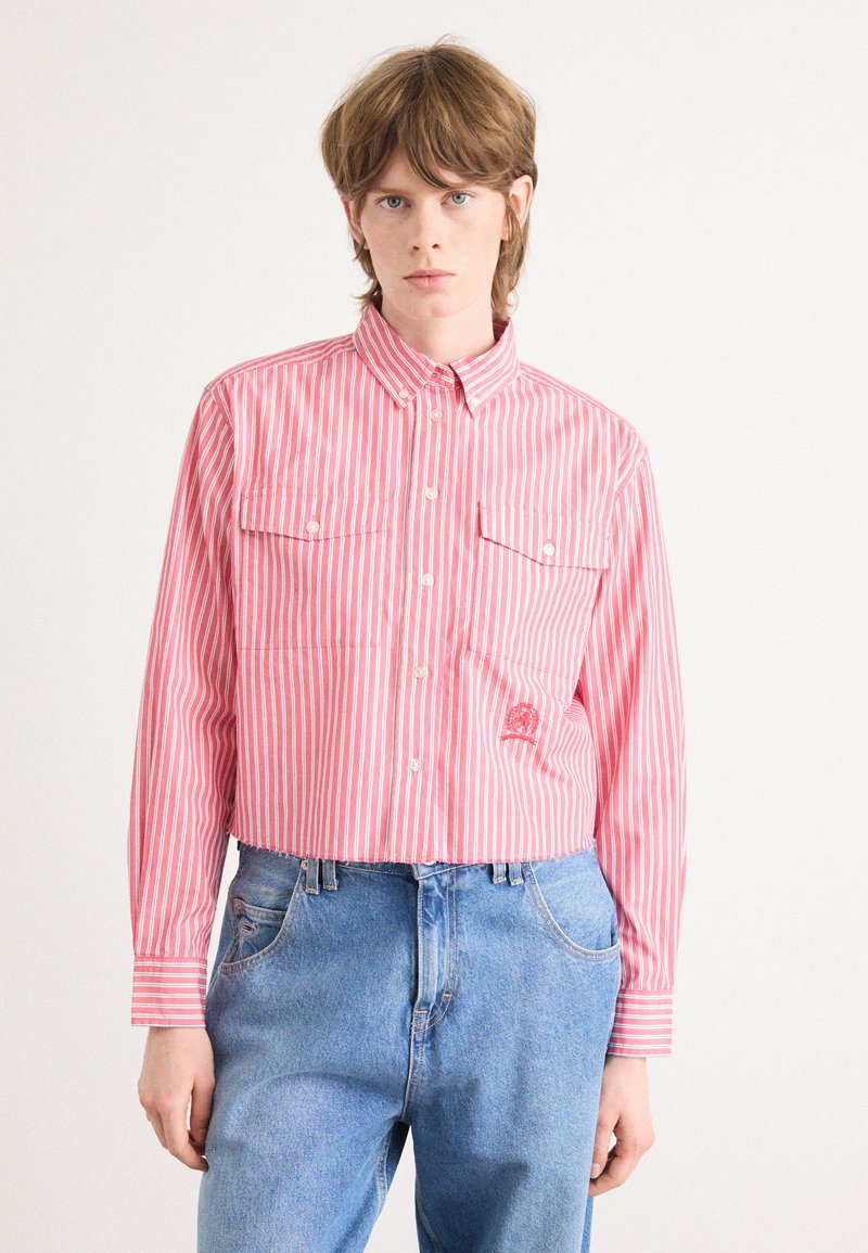 Randig skjorta i rosa och vitt, har en krage, två bröstfickor och en kortad design. Bärs med blå denimjeans.