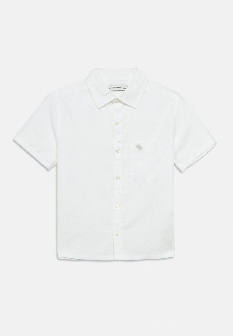 Λευκό πουκάμισο με κοντά μανίκια και κουμπιά, κατασκευασμένο από ελαφρύ ύφασμα. Διαθέτει τσέπη στο αριστερό στήθος με μικρή κεντημένη λεπτομέρεια λογότυπου.