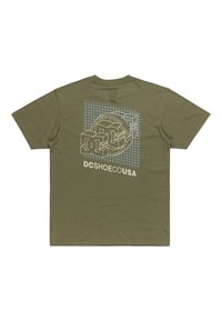 Olive green cotton T-shirt featuring a graphic design of the "DC" logo with grid lines and text "DCSHOECOUSA" printed in white.