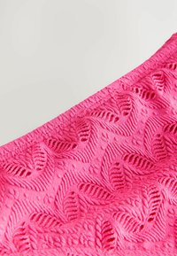 Helles pink strukturiertes Gewebe mit einem Blattmuster, das erhabene Elemente und eine weiche Oberfläche aufweist. Die Ränder sind elastisch für eine dehnbare Passform.
