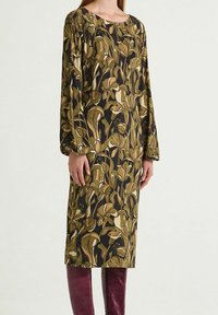 Abito a maniche lunghe con motivo floreale verde e beige su sfondo scuro. Realizzato in tessuto leggero, lunghezza al ginocchio.