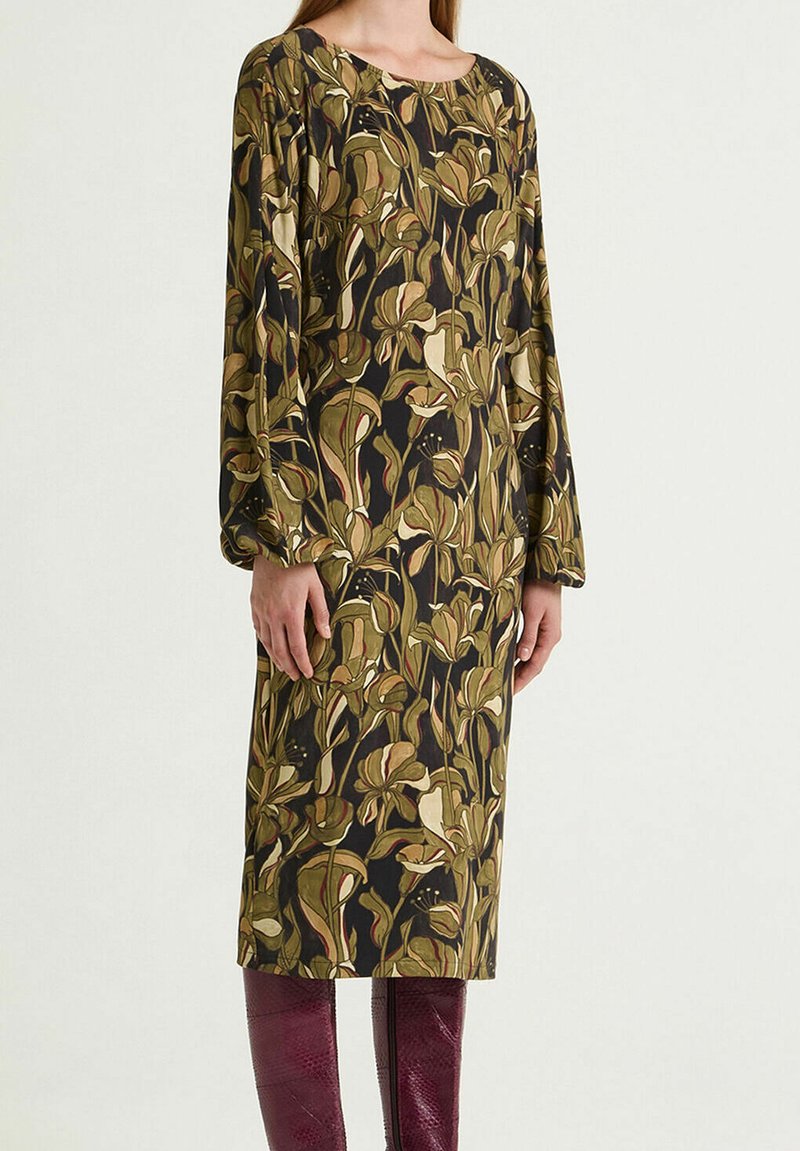Abito a maniche lunghe con motivo floreale verde e beige su sfondo scuro. Realizzato in tessuto leggero, lunghezza al ginocchio.