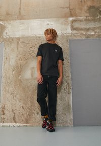 Puma PUMA STAPLE TEE - Apdrukāts T-krekls - puma black