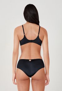 Czarny biustonosz bikini i wysoka talia o gładkiej fakturze. Biustonosz ma regulowane ramiączka i zapięcie na haczyk; dół ma detal w formie otworu.