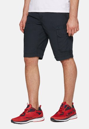 Marinefarbene Cargo-Shorts mit mehreren Taschen und gestickten Akzenten, kombiniert mit roten und schwarzen Sportschuhen mit strukturiertem Obermaterial und weißer Sohle.