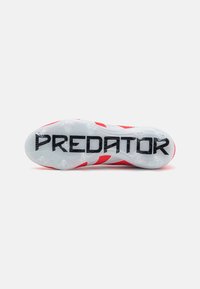 Crvena i bijela atletska obuća sa solema koja ima teksturiranu površinu, istaknuto "PREDATOR" brendiranje i specifične dizajne krampona za prianjanje.