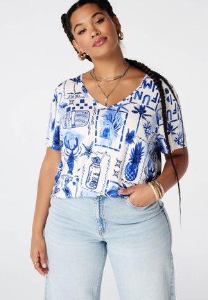 Vrouw met gevlochten haar draagt een blauw-wit T-shirt met korte mouwen met tropische en oceaanthema-print en lichtblauwe spijkerbroek.