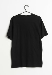 Camiseta de algodón negra en un gancho, de mangas cortas, con cuello redondo, textura suave, sin logotipos ni patrones visibles, colgando contra un fondo liso.
