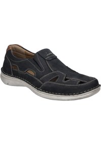 Schwarzer Leder-Slipper mit durchbrochenem Design, braunen Akzenten, beiger Naht und einer leicht strukturierten Sohle. Rundliche Zehenform und niedriges Profil.