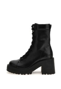 Bota de combate de cuero negro hasta la mitad de la pantorrilla con suela de plataforma gruesa, tacón bloque robusto, parte delantera con cordones y ojales de metal.