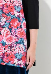 Blommig topp med ett livfullt rosa och blått blommönster på ett lätt tyg, kontrasterat med svarta ärmar, och en bekväm passform.