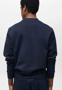 Sudadera azul marino con cuello redondo, puños y dobladillo acanalados. Fabricada en material suave, presenta un diseño limpio y minimalista sin adornos.