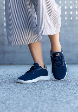 Granatowe siateczkowe trampki z szarymi akcentami, białymi podeszwami i okrągłymi sznurowadłami. Teksturowana cholewa i gładka gumowa podeszwa tworzą nowoczesny design.