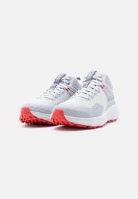 Ζευγάρι λευκά και γκρι αθλητικά παπούτσια με έντονη πορτοκαλί σόλα, πλέγμα στα επάνω μέρη και κορδόνια, εμφανιζόμενα από μπροστινή πλευρά σε λευκό φόντο.