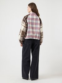 Karirana jakna z mešanico rjavih in roza kvadratov, z ovratnikom in sproščenim krojem, kombinirana s širokimi črnimi hlačami.