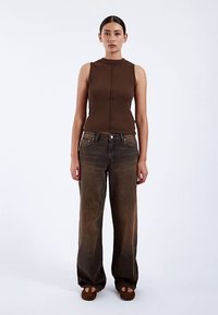 Brown ribbed sleeveless top paired with loose-fitting, faded dark brown jeans, featuring a straight-leg design and subtle hardware accents.