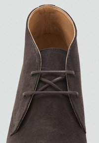 Chaussure en suede gris foncé avec un bout arrondi, dotée d'un intérieur en cuir lisse et d'un design de laçage simple avec des lacets fins.