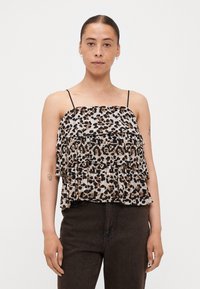 Luipaardprint mouwloze top met drie gerimpelde lagen, lichte stof, dunne zwarte banden en een elastische buste. Gemaakt in combinatie met donkere spijkerbroeken.