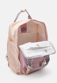 Jasnoróżowy i lawendowy plecak wykonany z tkaniny, z zamykaną na zamek przednią kieszenią oraz wewnętrzną siateczkową przegródką. Posiada metkę z logo w środku.