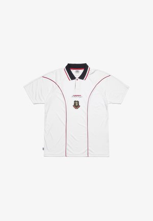 Cămașă polo albă cu mâneci scurte, guler negru și detalii roșii. Prezintă un emblema cu leu și logo-ul „Umbro” pe față. Textură de material neted.