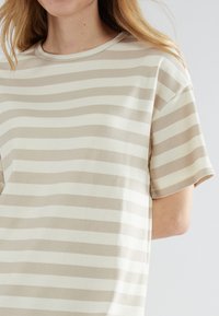 Beige och ljuskrämrandig t-shirt, kort ärm, ribbad textur, rund halsringning, avslappnad passform, mjukt tyg.