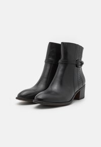 Bottines en cuir noir avec une finition lisse, bout arrondi, talon carré et une sangle décorative avec un accent texturé.
