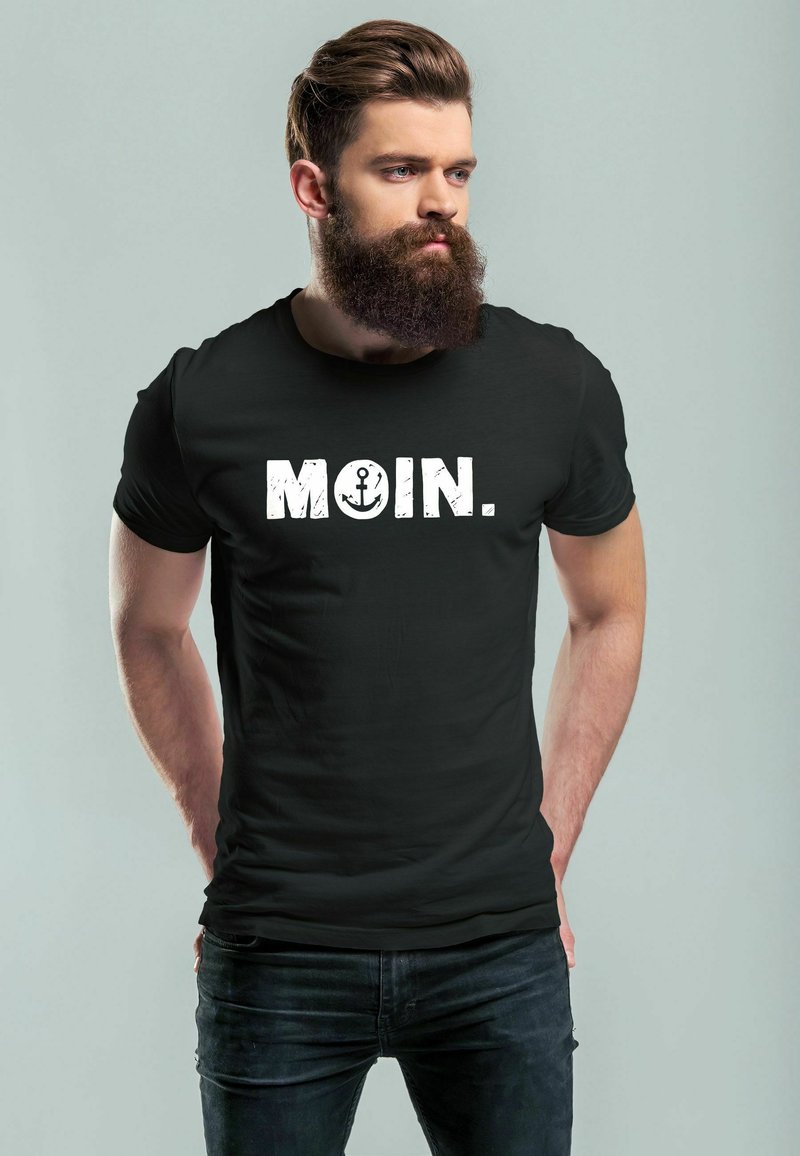 Schwarzes Baumwoll-T-Shirt mit dem Wort "MOIN." in fetten, weißen, abgenutzten Buchstaben und einem Anker-Graphic. Unisex-Design mit kurzen Ärmeln.