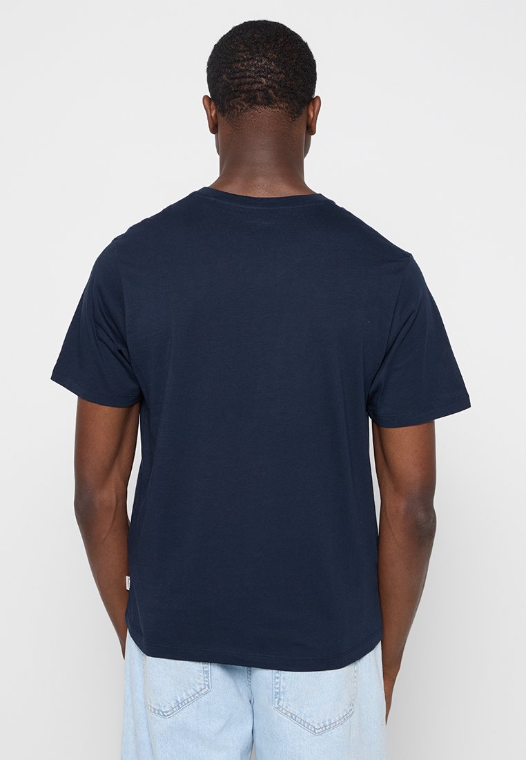 Camiseta de algodón azul marino con mangas cortas, escote redondo y un dobladillo recto. Diseño minimalista sin adornos visibles.