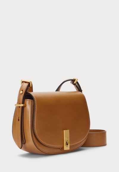 pruun nahast sadulakott, millel on kõver kuju, kullatud riistvara ja logo aktsent. Omab eemaldatavat rihma mitmekesiste kandmisvõimaluste jaoks.