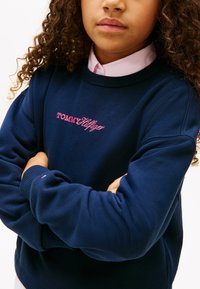 Μπλε φούτερ με ροζ κέντημα "TOMMY HILFIGER". Διαθέτει μανσέτες και τελείωμα με ριμπ, στρογγυλή λαιμόκοψη και απαλή υφή.