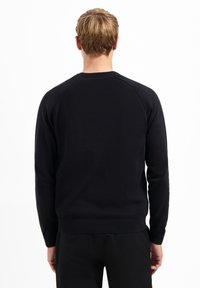 Schwarzer Strickpullover mit Rundhalsausschnitt und gerippten Bündchen. Verfügt über eine glatte Textur und Raglanärmel, von hinten betrachtet.