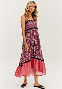 Maxi sukienka z fioletowo-różowym wzorem paisley, czarnym falbanym wykończeniem i warstwowym krojem z luźną spódnicą.