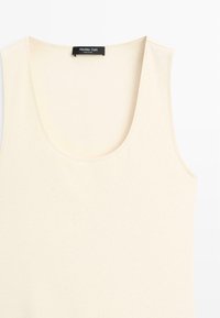 Crèmekleurige geribde mouwloze tanktop met ronde halslijn en Massimo Dutti-label aan de kraag.