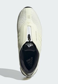 Αθλητικό παπούτσι σε κρεμ χρώμα με δομημένο διχτυωτό πάνω μέρος, κλείσιμο με φερμουάρ, μαύρο εσωτερικό και ασημένιες λεπτομέρειες λογότυπου. Στρογγυλή μύτη και επενδεδυμένος γιακάς.