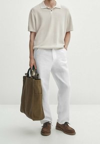 Beige lyhythihainen poolopaita, valkoiset housut, ruskeat mokkanahkakengät ja ruskea kangaskassi, jossa mustat kahvat ja ulkopuoliset taskut.