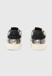Un paio di sneaker basse con motivo in serpente e linguette in suede nero, viste dal retro su uno sfondo grigio semplice.
