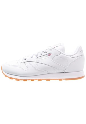 Weiße Leder-Laufschuhe mit strukturierter Oberfläche, gummierter oranger Laufsohle und Reebok-Logo an der Seite und auf der Zunge. Standard Schnürverschluss.