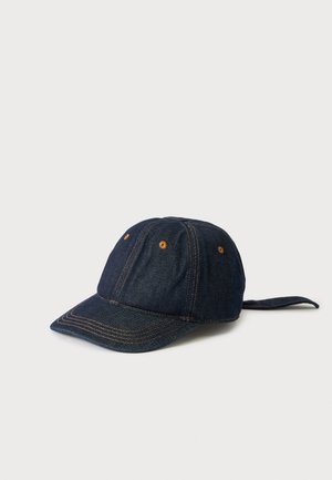 Donkerblauwe denim baseballpet met bruine stiksels en ventilatieoogjes, afgebeeld op een effen lichte achtergrond.