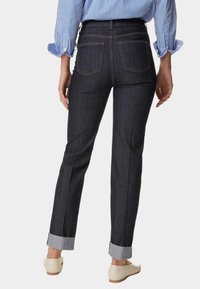 Jeans de mezclilla oscuro con un corte recto, puños doblados y dos bolsillos traseros. Presenta detalles de costura y una textura suave.